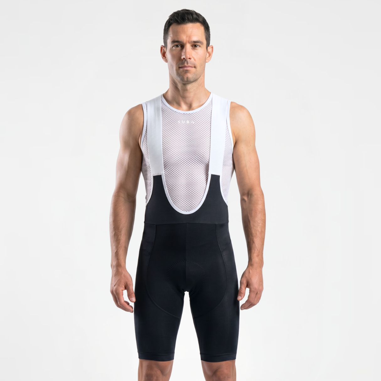 Man wearing black cycling bibs with white straps and a mesh cycling base layer under shirt.