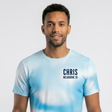 A man wearing a light blue and white tie-dye t-shirt with 'CHRIS MELBOURNE 26' printed in black on the chest, set against a plain light gray background.