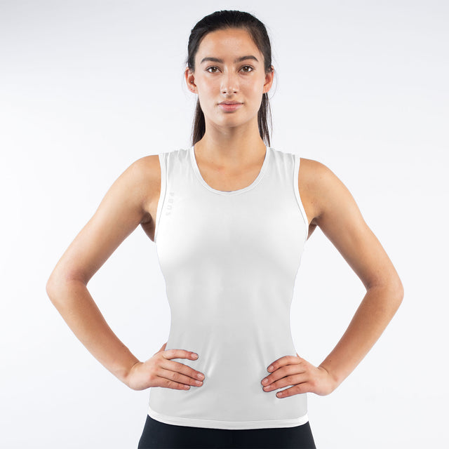 Woman wearing a white tank top against a plain background