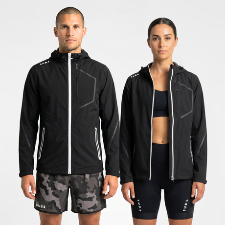 Man and woman wearing black waterproof jackets and shorts with SUB4 branding on a white background