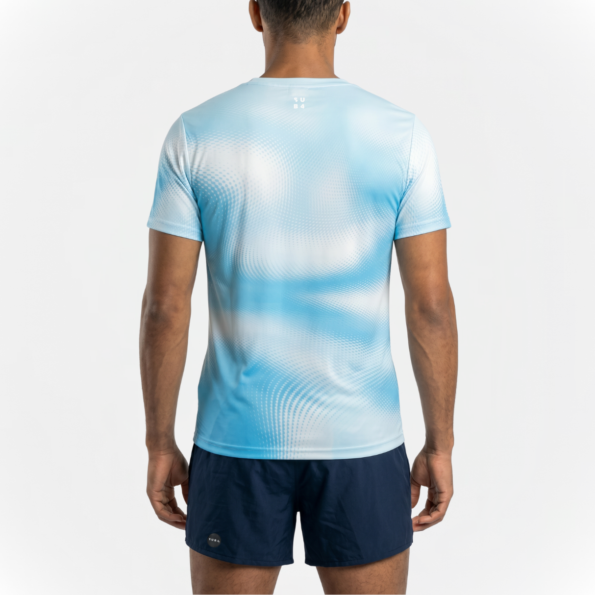 Back view of person wearing a sky blue running t-shirt with patterns and navy running shorts on a white background