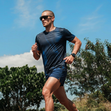 Man running outdoors with trees and blue sky in the background