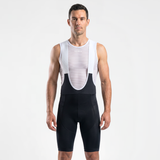 Man wearing black cycling bibs with white straps and a mesh cycling base layer under shirt.