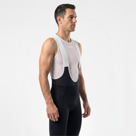 Side view of man wearing black cycling bibs with white straps and a mesh cycling base layer under shirt.