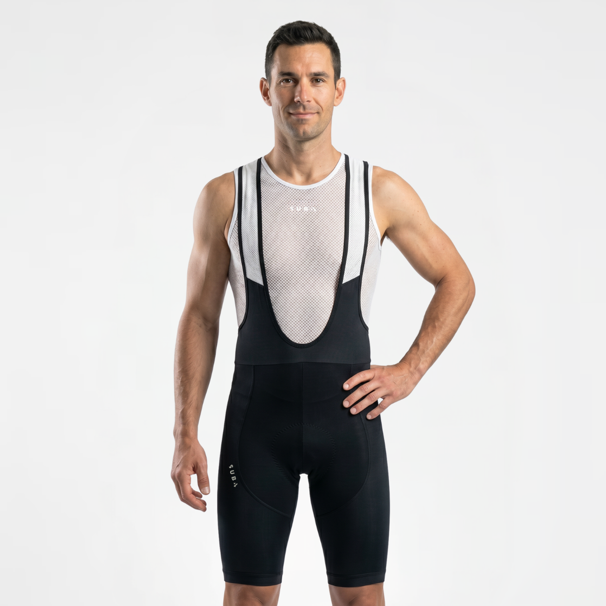 Man wearing a classic black and white cycling bib with a white mesh cycling base layer on a light gray background