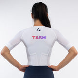 Person wearing a white trisuit with 'TASH' personalised name print on a light gray background