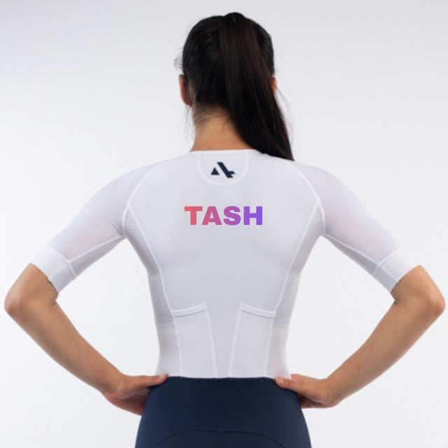 Person wearing a white trisuit with 'TASH' personalised name print on a light gray background