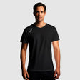 Man wearing a black t-shirt with a brand logo on a gray background