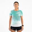 Woman wearing a gradient teal running t-shirt and black running shorts on a white background