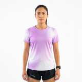 Woman wearing a lilac gradient running t-shirt and black running shorts on a white background