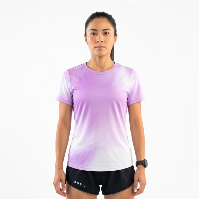 Woman wearing a lilac gradient running t-shirt and black running shorts on a white background