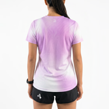 Back view of woman wearing a lilac gradient running t-shirt and black running shorts on a white background.