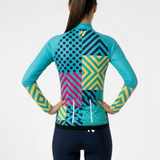 Woman wearing a colorful cycling jersey with geometric patterns and navy cycling shorts on a white background
