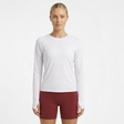 Woman wearing a white long-sleeve running fitness top and maroon shorts on a white background