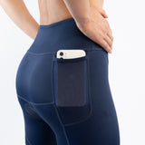 Navy blue athletic triathlon shorts with a pocket holding a phone on a white background
