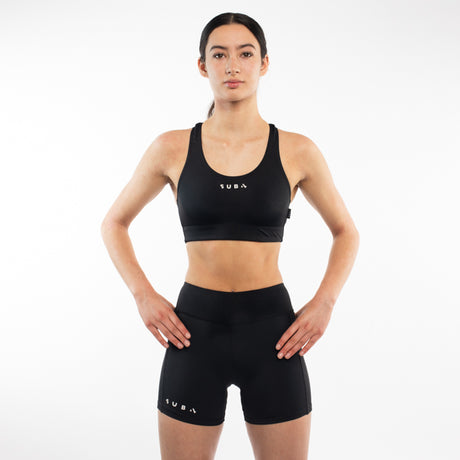 Woman wearing a black sports bra and shorts with 'SUB4' branding on a white background