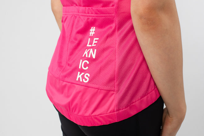 Person wearing a bright pink sleeveless top with '#LEKNICKS' text on a light gray background