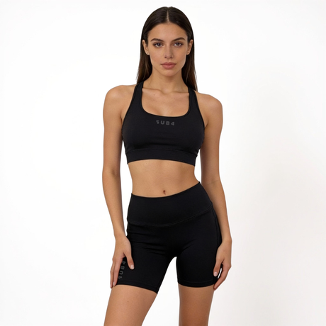 Woman wearing a black sports bra and athletic shorts set on a white background