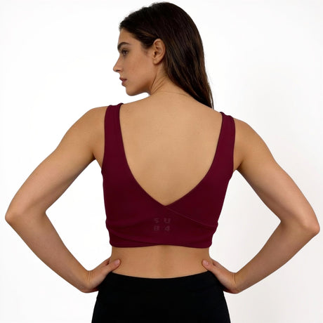Woman wearing a red maroon sports bra on a white background