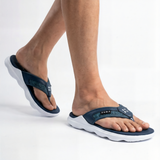 Navy sandals with white soles worn by a person on a light gray background