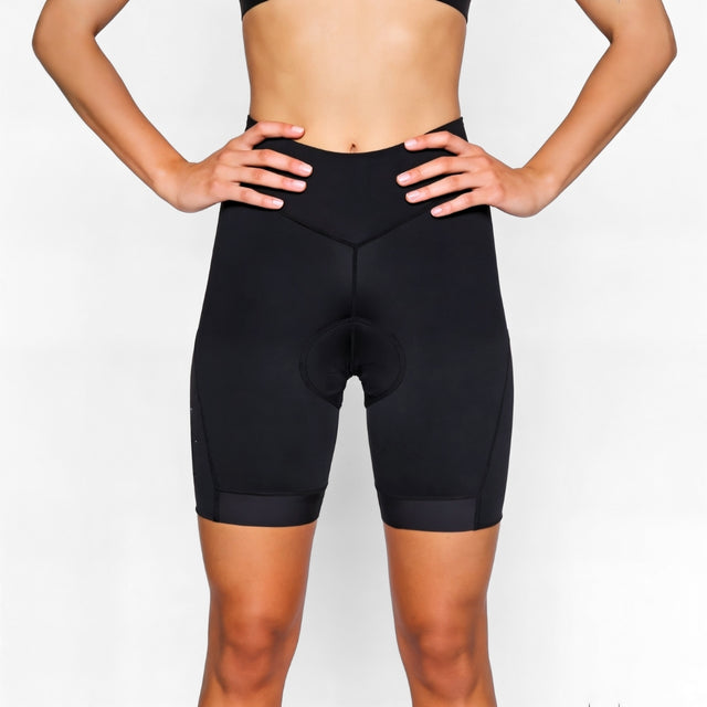 Person wearing black athletic cycling shorts on a plain background